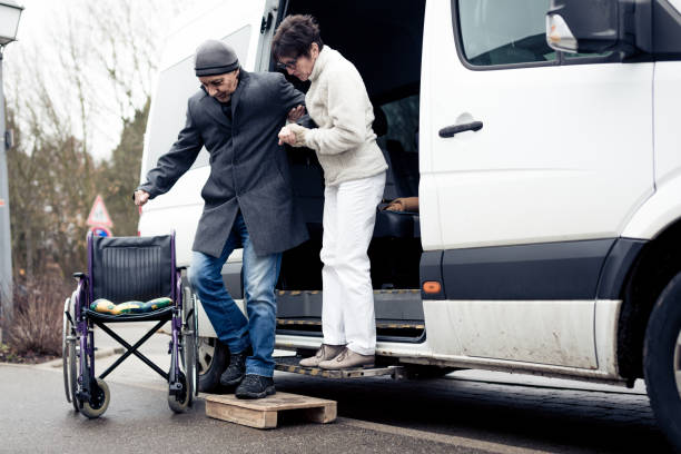 nurse helping senior man exit a van and get to his wheelchair